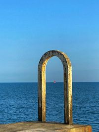 Scarlet sails. scenic view of sea against clear blue sky and fishing boat in arch.