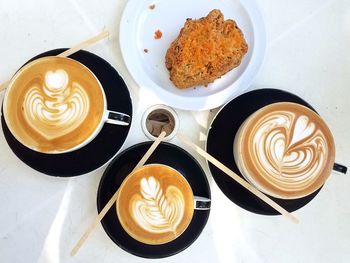 High angle view of coffee cups with sweet food served on table