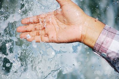 Cropped hand touching spraying water