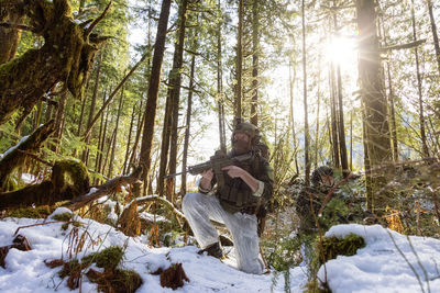 Man sitting by tree trunk in forest