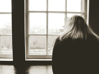 Rear view of woman looking through window at heptonstall museum