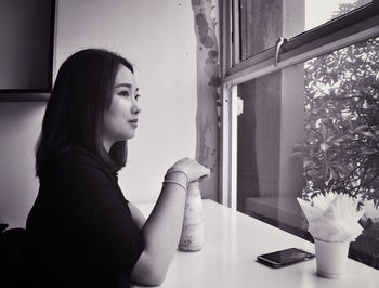 Young woman sitting on table at home