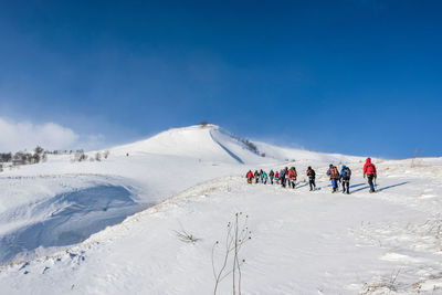 People walking on snow against sky