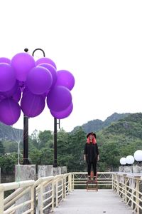 Rear view of woman with balloons standing against sky