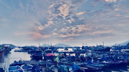 Boats moored in harbor at sunset