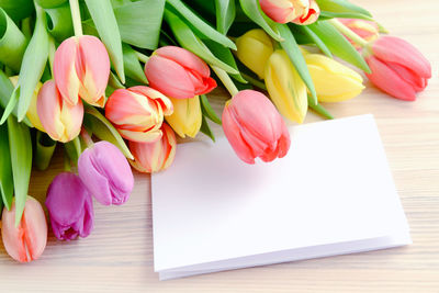 Close-up of tulips and greeting card on table