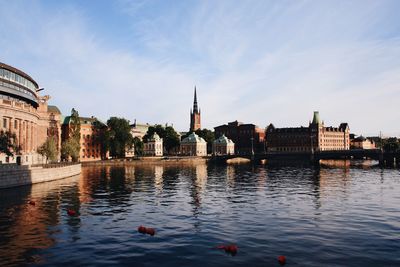Ducks swimming in river by city against sky