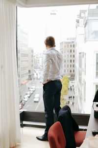 Businessman on the phone in office looking through window