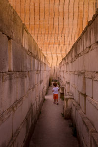 Rear view of woman walking on cobblestone street