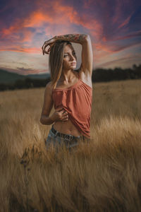 Woman standing on field against sky during sunset