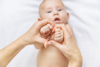 Cropped hands of mother holding baby girl at home