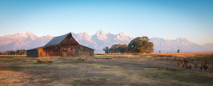 Built structure on field by mountain against sky