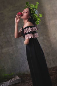 Young woman looking away while standing against plants