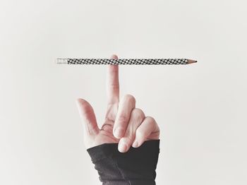 Close-up of person hand holding cross against white background