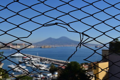 Close-up of chainlink fence by sea against sky