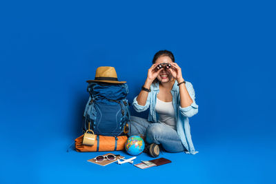 Young woman wearing sunglasses against blue background