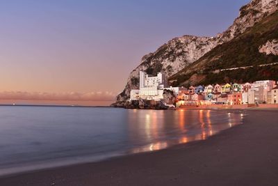 Scenic view of sea and buildings against clear sky