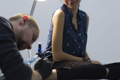 Artist making tattoo on woman leg