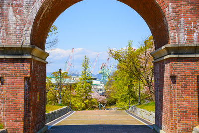 Trees and buildings against sky seen through arch window