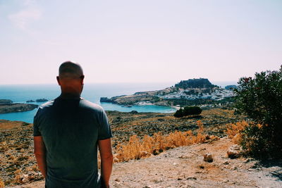 Rear view of man looking at sea against sky