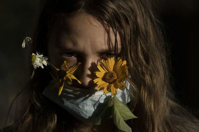 Close-up portrait of girl with yellow flowering plant