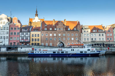 Boats moored on river against buildings in city