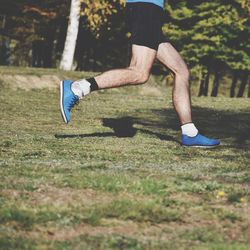 Low section of athlete jogging on field