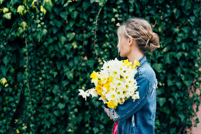 Rear view of woman standing on yellow flowering plants