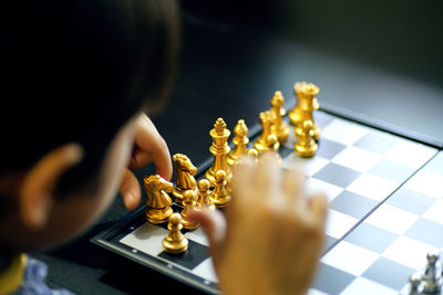 High angle view of hand holding chess piece onboard