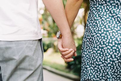 Midsection of couple holding hands