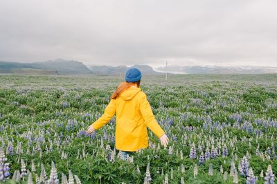 Rear view of woman standing on field against sky