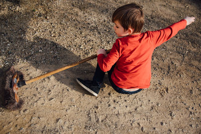 Rear view of boy sweeping field with broom