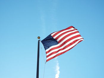 Low angle view of flag against clear blue sky