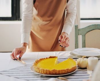 Midsection of woman holding while sitting on table at home