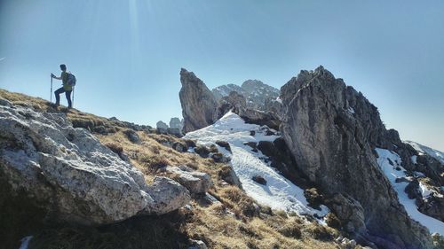 Low angle view of man standing on rock against sky