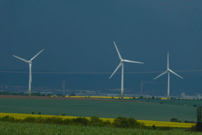 Wind turbines on field against clear sky