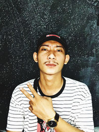 Portrait of young man standing against black background