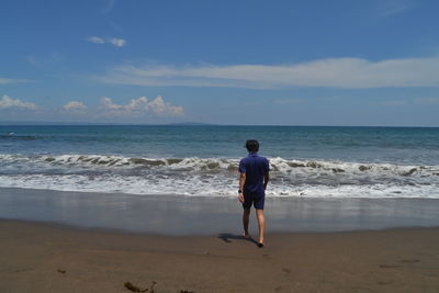 Rear view of man walking towards shore at beach