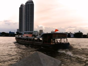 Nautical vessel on sea by buildings against sky in city