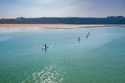 People paddleboarding in sea against sky