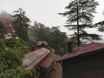 Houses and trees in city against sky