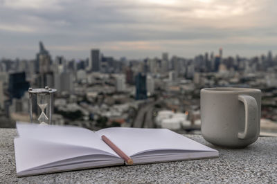 Close-up of open book on table against buildings in city