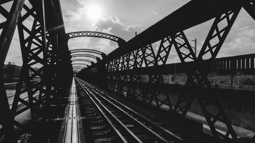 Bridge over railroad tracks against sky