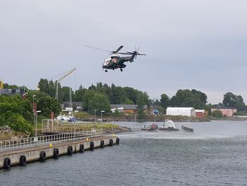 Helicopter flying over river against sky