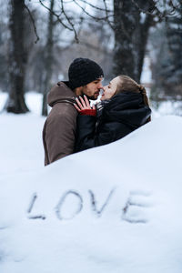 Winter outdoors portrait of young couple in love and word love on snow. valentines day outdoors