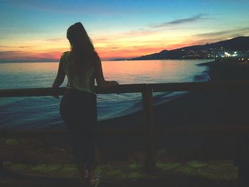 Silhouette woman standing on beach against sky during sunset