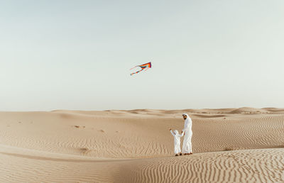 Full length of father with son flying kite in desert