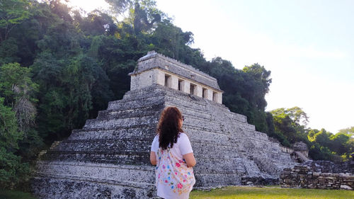 Rear view of woman standing by tree against sky