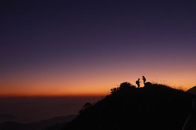 Silhouette people standing against sky during sunset