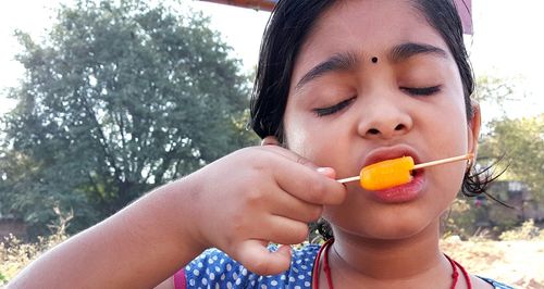 Close-up of girl with eyes closed eating ice candy